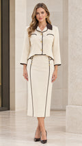Front view of model wearing cream two-piece skirt suit set with dark contrast trim and gold buttons