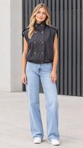 Front view of model wearing black double-breasted high-neck utility vest with light wash jeans